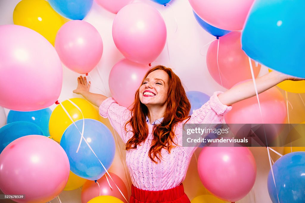 Mujer joven de pie en muchos globos