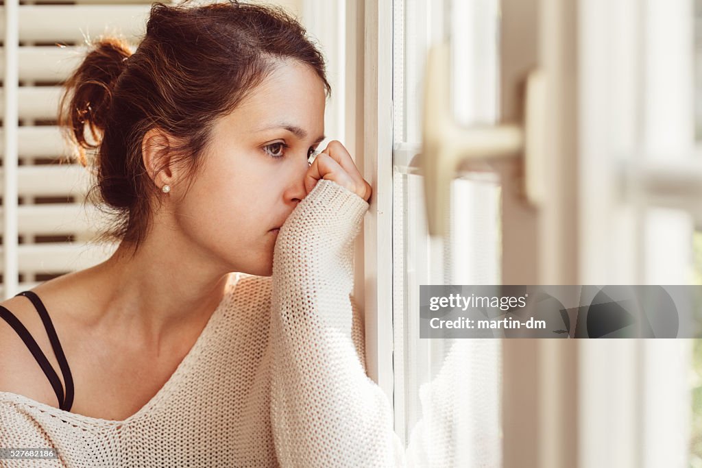 Ein deprimierter Frau schaut durch Fenster