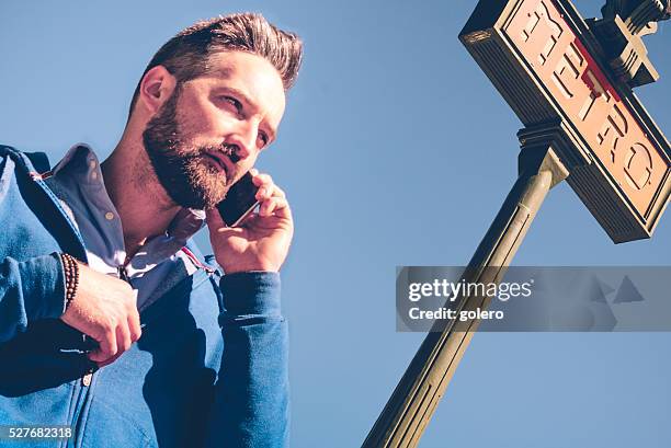 beautiful bearded man talking with mobile at paris metro sign - paris metro sign stock pictures, royalty-free photos & images