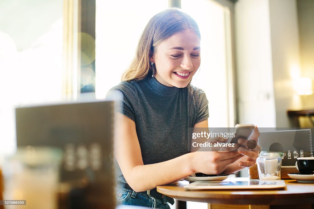 Schöne junge Frau im Café mit Smartphone