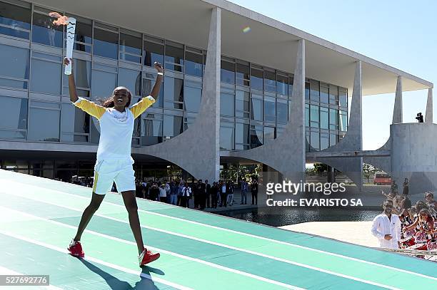 Brazilian volleyball player Fabiana Claudino carries the Olympic torch at Planalto Palace in Brasilia following the flame's arrival in the country on...