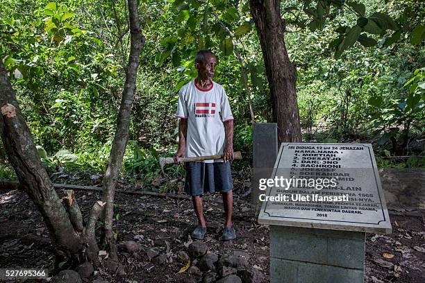 Sukar, 83 years old, a villager who witnessed Indonesia's anti-communist massacre, stands next to the tombstone which was installed by activists and...