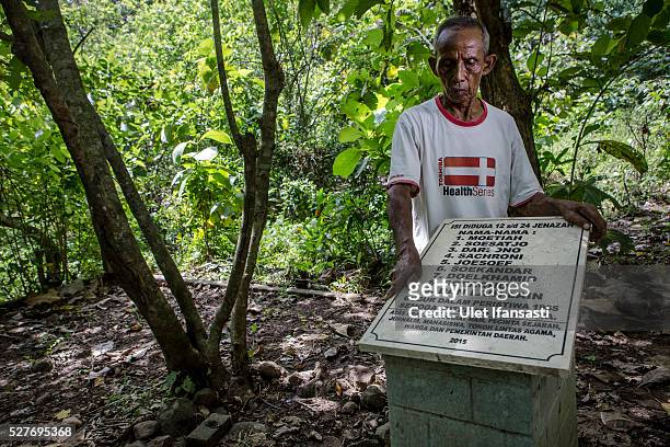 Sukar, 83 years old, a villager who witnessed Indonesia's anti-communist massacre, stands next to the tombstone which was installed by activists and...