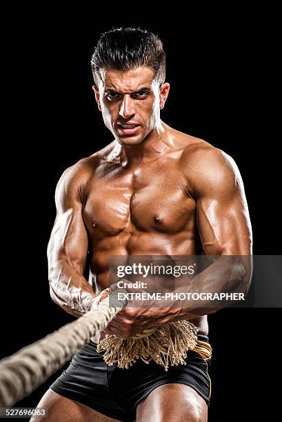 man pulling the rope - male athlete with rope on black background stock pictures, royalty-free photos & images