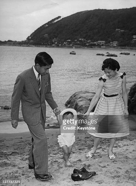 Prince Hiro walking on the beach near the Hayama Imperial Villa, Japan, with his parents, Crown Prince Akihito and Princess Michiko, 29th June 1961.
