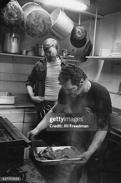 Firefighters cooking in a firehouse, USA, circa 1980.