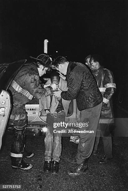 Firefighters helping a boy breathe with an oxygen mask, USA, circa 1980.