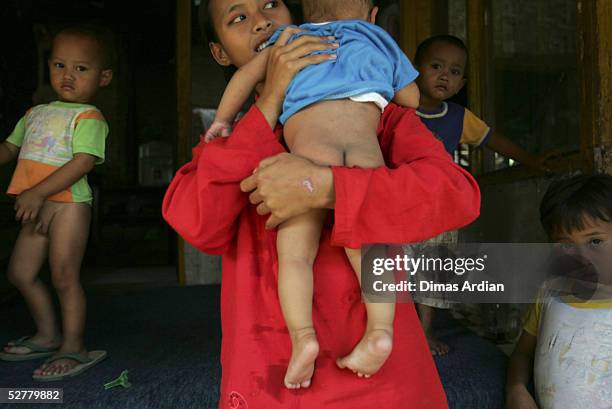 Suspected-polio-child Ramdhan, 7-months-old, is carried by her mother May 9, 2005 at Girijaya village, Sukabumi, Indonesia. Indonesian health...