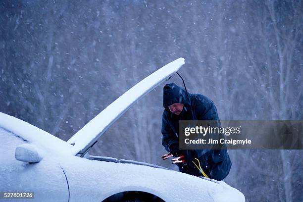 man jump starting car in snow - jumper cables stock pictures, royalty-free photos & images