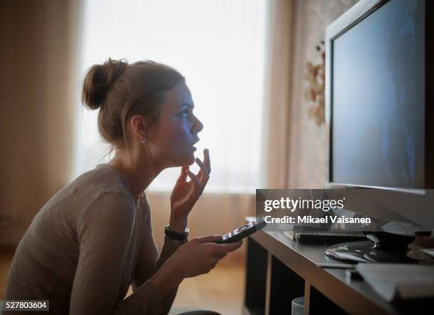 young woman looking in suspense at tv - begeistert fernsehen stock-fotos und bilder