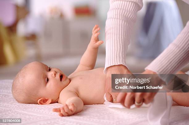 putting a cloth diaper on baby - cloth nappy stock pictures, royalty-free photos & images