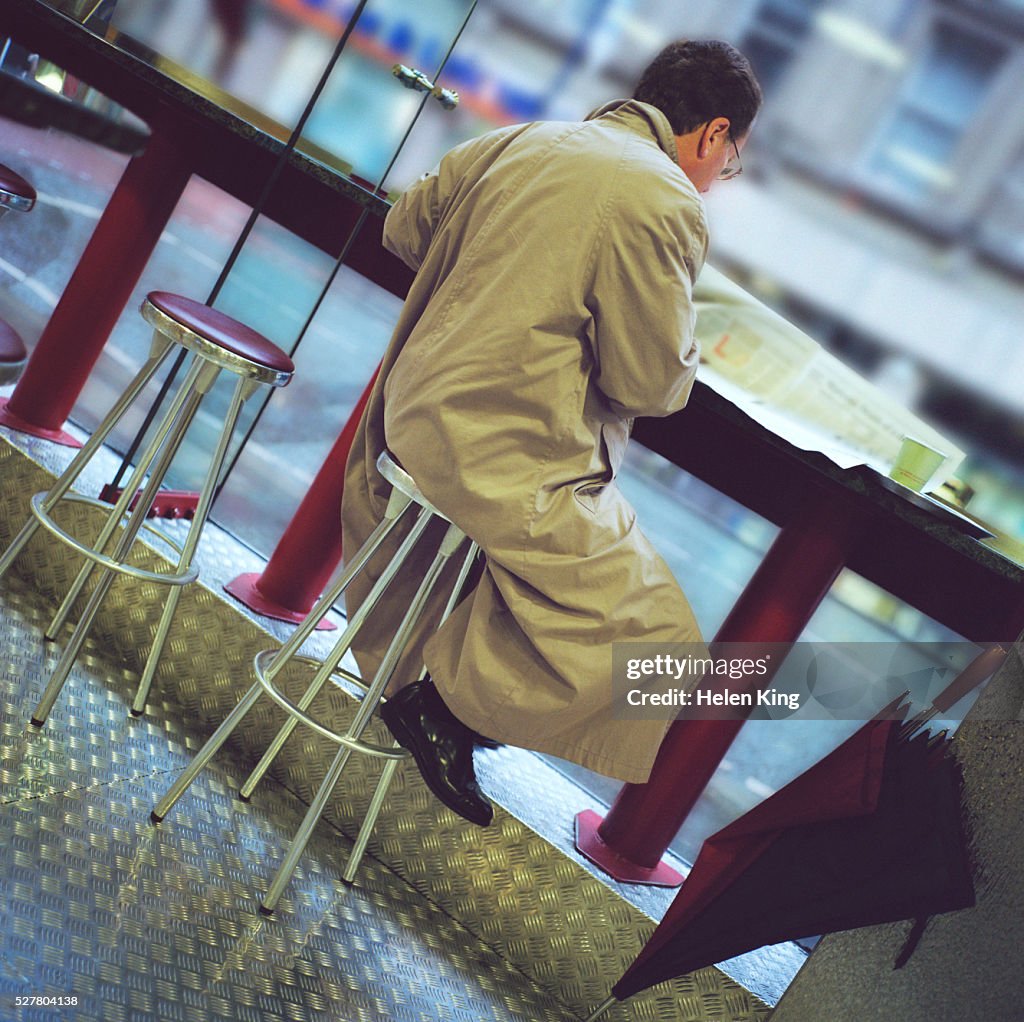 Businessman Reading Newspaper in Manchester Cafe
