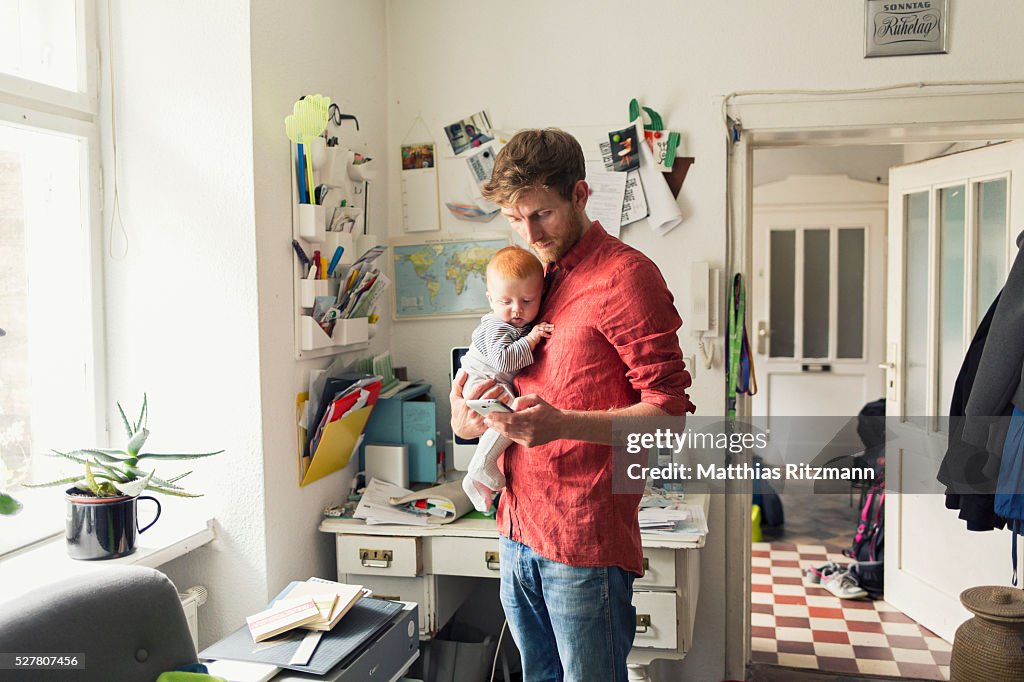 Father with baby son (12-23 months) using smart phone
