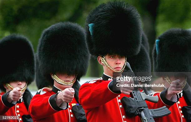 Guardsmen of the Household Division, dressed in ceremonial uniforms topped off with the iconic bearskin hat, march on the courtyard of Buckingham...