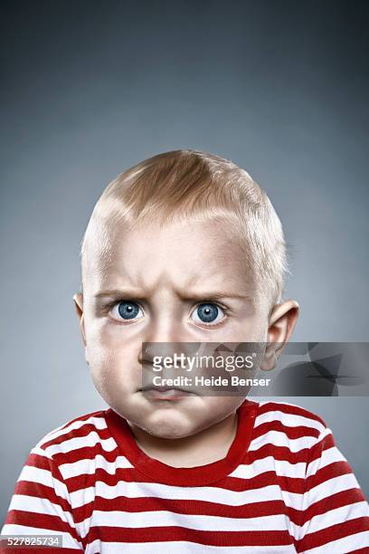 angry looking baby boy in striped shirt - baby attitude stock pictures, royalty-free photos & images