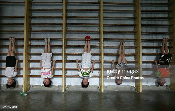 Children hang upside down as they practise diving movements at a diving school on May 10, 2005 in Chengdu of Sichuan Province, China. There are...