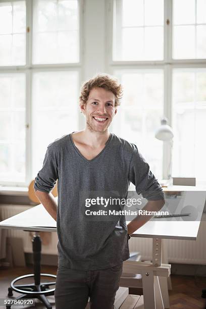 portrait of confident male fashion designer in his studio - mann lachen blick in die kamera stock-fotos und bilder