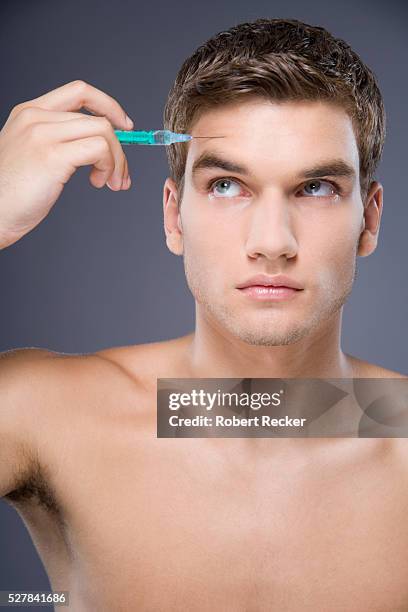 man injecting forehead with botox - men plastic surgery stock pictures, royalty-free photos & images
