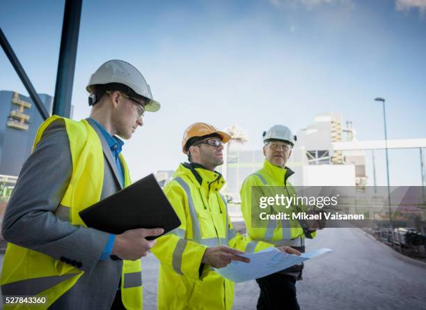 engineers on modern power station construction site - protective workwear photos et images de collection
