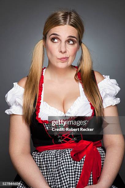 studio shot of blond haired woman making face - dirndl stock-fotos und bilder