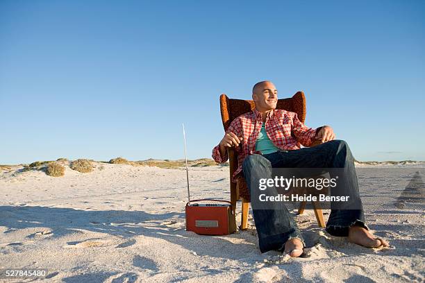 young man sitting in an armchair on the beach - actividad de fin de semana fotografías e imágenes de stock