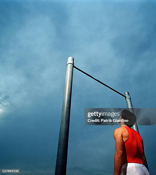 gymnast gazing up at high bar - reck stock-fotos und bilder