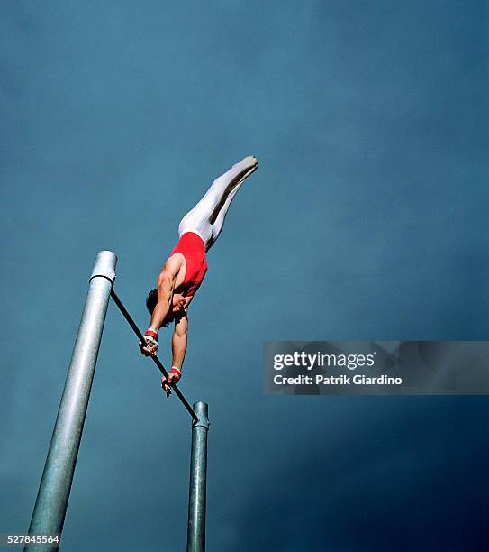 gymnast performing routine on high bar - gymnast stock pictures, royalty-free photos & images