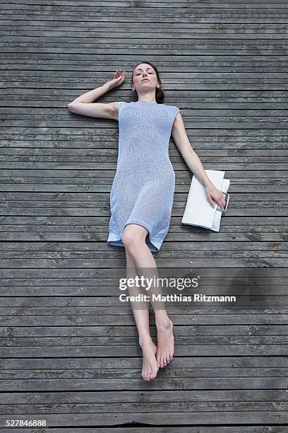 young woman lying on pier - women lying imagens e fotografias de stock