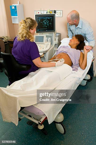 couple looking at ultrasound of twin babies - twin ultrasound stock pictures, royalty-free photos & images
