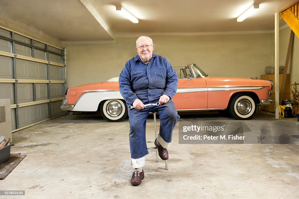 Portrait of senior man with classic vintage car in garage