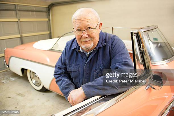 portrait of senior man with classic vintage car in garage - senior blaumann stock-fotos und bilder