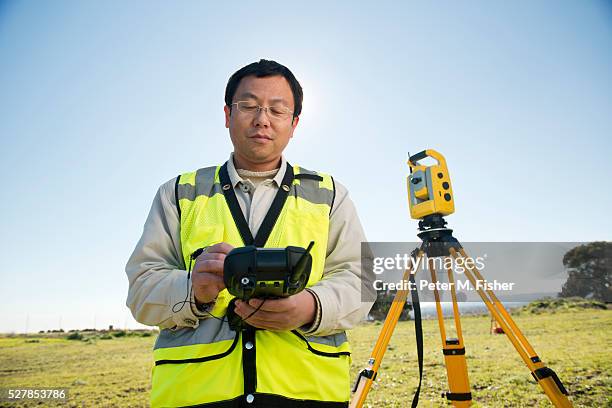 surveyor checking readings from theodolite - theodolite stock pictures, royalty-free photos & images