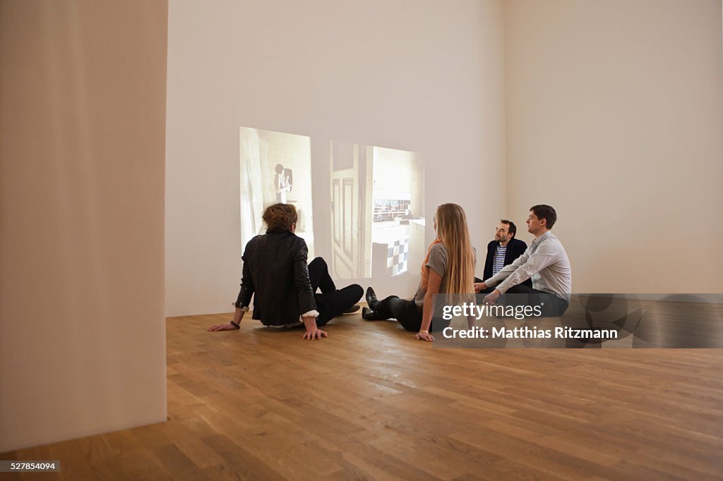 Friends watching movie projected on wall