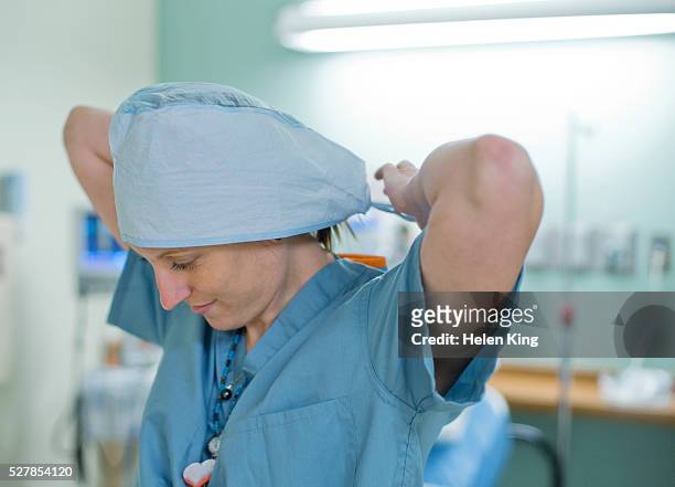 nurse tying on surgical hat - nurse hat stock pictures, royalty-free photos & images