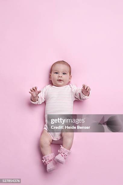 baby girl (6-11 months) lying on pink ground - cute baby studioshot stock-fotos und bilder