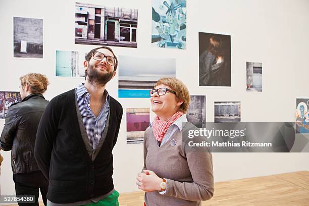 people watching exhibition of photos - exhibition stock-fotos und bilder