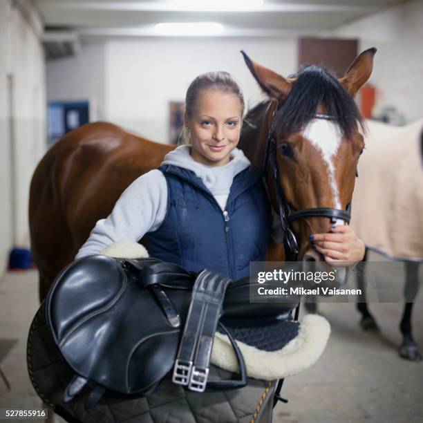 portrait of young woman with horse in stables - saddle stock pictures, royalty-free photos & images