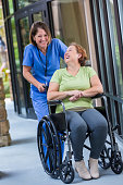 Happy nurse pushing patient in wheelchair after hospital discharge