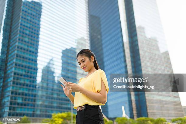 asian woman reading text messages at outdoor - beautiful filipino women stock pictures, royalty-free photos & images