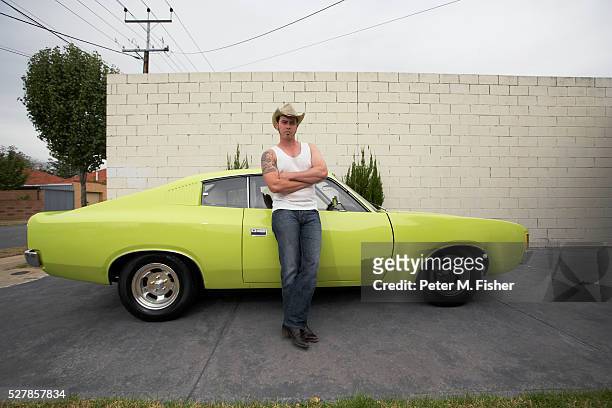man with cowboy hat leaning on muscle car - sportwagen stock-fotos und bilder