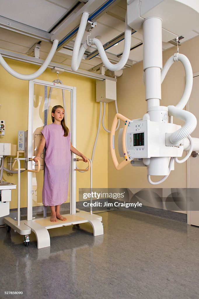 Girl (10-12) having anterior-posterior of complete spine to assess scoliosis using digital diagnose general radiography machine