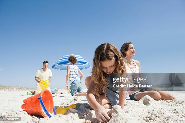 little girl building a sandcastle - family summer holiday stock-fotos und bilder