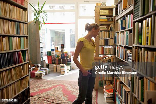 woman looking at books in bookstore - libreria fotografías e imágenes de stock
