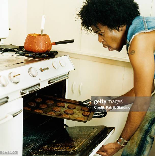 man removing cookies from oven - brulé photos et images de collection