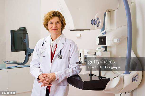 smiling medical technician leaning on mammography machine - mammogram stock pictures, royalty-free photos & images