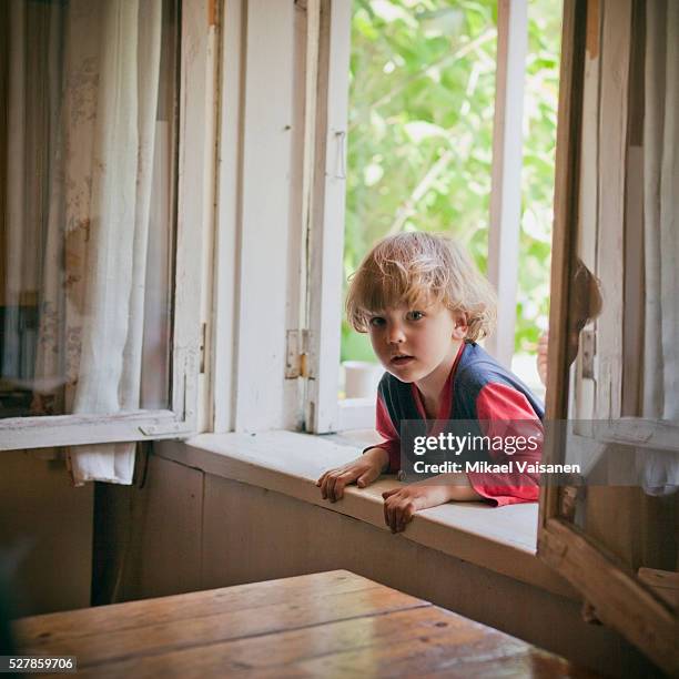 boy (3-4) peeking through window into house - peep window stock pictures, royalty-free photos & images