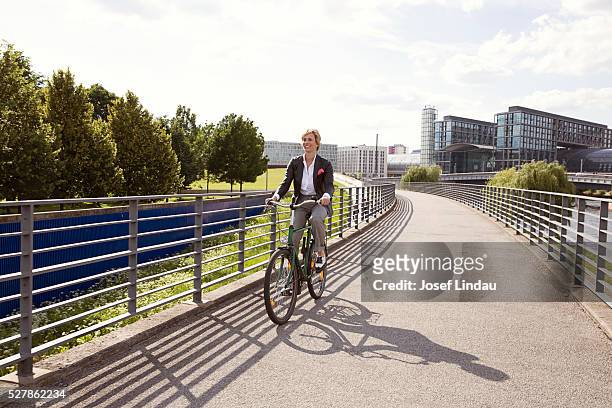view of woman riding bike - ballustrade stockfoto's en -beelden