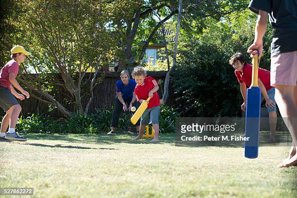 boys playing cricket in backyard - family cricket stockfoto's en -beelden