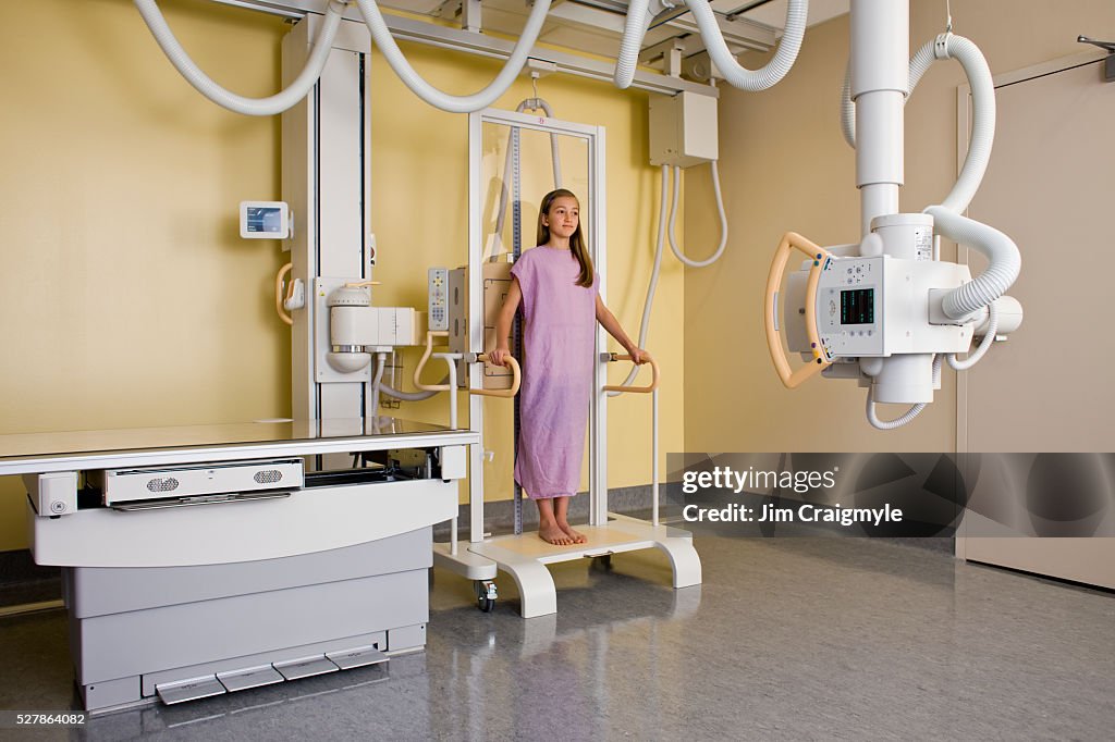 Girl (10-12) having anterior-posterior of complete spine to assess scoliosis using digital diagnose general radiography machine