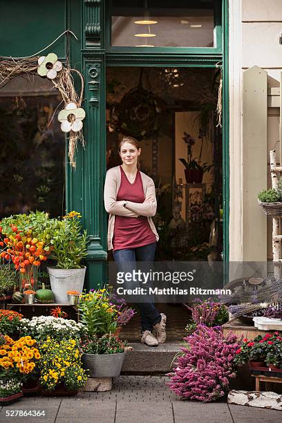 flower vendor in doorway of shop - florista fotografías e imágenes de stock